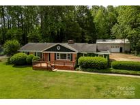 Charming brick home featuring a lovely front deck, manicured lawn and mature trees at 5100 Crestland Ave, Charlotte, NC 28269