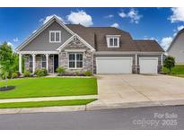 Charming two-story home featuring stone accents, a three-car garage, and a well-manicured lawn at 7049 Irongate Dr, Indian Land, SC 29707