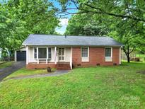 Charming single-story home featuring a brick facade, well-maintained lawn, and mature trees at 7412 Woodstream Dr, Charlotte, NC 28210