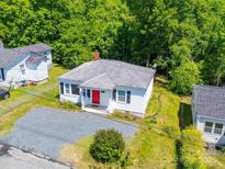 Charming single-story home with a bright red door and gravel driveway surrounded by lush greenery at 83 Woodsdale Se Pl, Concord, NC 28025