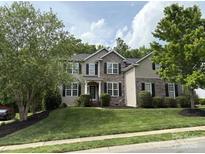 Charming two-story home with a well-manicured lawn, stone accents, and mature trees at 10008 King George Ln, Waxhaw, NC 28173