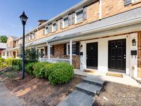 Charming brick townhome featuring a well-maintained front yard and covered porch, perfect for relaxation and curb appeal at 1348 Green Oaks Ln # L, Charlotte, NC 28205