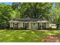 Charming brick ranch home with a manicured lawn, black shutters, and a vibrant teal front door at 1700 Emerywood Dr, Charlotte, NC 28210