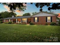 Charming brick home with black shutters, manicured lawn, and covered front porch at sunset at 301 Museum Rd, Statesville, NC 28625