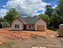 New construction home featuring a modern roof and an attached, unfinished two-car garage on a spacious lot at 302 W Second St, Lowell, NC 28098
