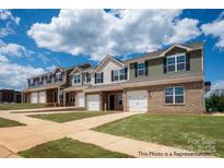 Newly constructed townhomes showcasing brick and siding, complemented by attached garages and manicured lawns at 5153 Tommy Ln # 1104, Stanley, NC 28164