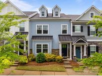 Charming townhome featuring blue siding, stone accents, dormer windows, and manicured landscaping in a well-maintained community at 15021 Meacham Farm Dr, Huntersville, NC 28078