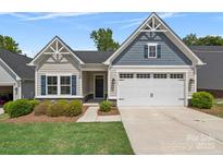 Charming home featuring a two-car garage, manicured lawn, and stylish architectural details under a bright blue sky at 1747 Slippery Rock Ln, Monroe, NC 28112