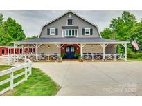 A beautiful farmhouse-style barn with stone accents, a covered porch, and a spacious concrete driveway at 3091 Old Meeting House Rd, Sharon, SC 29742