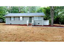 Charming single-story home featuring a gray brick facade, a well-maintained yard, and a cozy front porch at 402 Gibson Park Dr, Huntersville, NC 28078