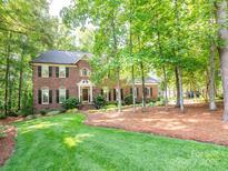 Charming two-story brick home with a lush green lawn and mature trees at 5417 Bedfordshire Ave, Harrisburg, NC 28075