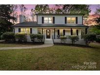 Charming two-story home with a covered front porch, landscaped yard, and fresh white and black paint at 5910 Grosner Pl, Charlotte, NC 28211