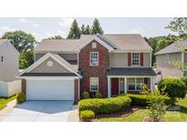 Traditional two-story home featuring red shutters, brick accents, a two-car garage, and manicured landscaping at 10815 Mountain Springs Dr, Charlotte, NC 28278