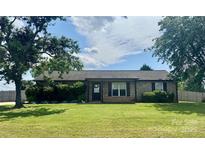 Charming brick home with a well-manicured lawn, mature trees, and beautiful landscaping at 133 Pheasant Run Rd, Troutman, NC 28166