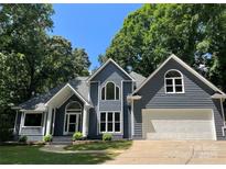 Charming two-story home featuring a front-facing garage, gray siding, and a well-manicured lawn surrounded by mature trees at 26056 Neptunes Lndg, Fort Mill, SC 29708