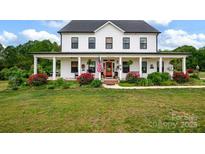 Charming two-story farmhouse with a welcoming wraparound porch and vibrant landscaping at 355 Cal Kennedy Rd, Cleveland, NC 27013