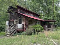 Rustic log cabin with a striking red roof, surrounded by lush greenery at 506 Waring Ct, Fort Mill, SC 29707