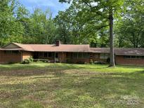 Ranch-style home with brick exterior, green shutters, and a well-maintained lawn and mature trees surrounding the property at 703 S Highway 27 Hwy, Stanley, NC 28164