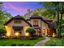 Charming two-story home with landscaped yard and stone walkway, illuminated by exterior lighting at dusk at 8534 Highgrove St, Charlotte, NC 28277
