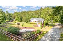Beautifully landscaped yard with charming home, wooden fence and mature trees at 120 Mossy Rock Trl, Iron Station, NC 28080