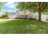 Charming home featuring a well-manicured lawn, inviting porch, and mature shade tree at 13223 Willow Breeze Ln, Huntersville, NC 28078