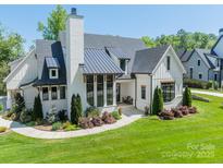 Stunning two-story home featuring a modern design with a metal roof, white brick and a perfectly manicured front lawn at 14228 Ryker Way, Davidson, NC 28036
