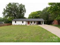 Charming single-story home featuring a vibrant red front door, a well-manicured lawn, and a convenient attached carport at 1537 Spangler Dr, Shelby, NC 28150