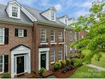 Charming brick townhome featuring a classic facade, black shutters and door, dormer windows, and well-manicured landscaping at 16930 Summers Walk Blvd, Davidson, NC 28036