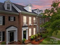 Charming brick townhome featuring manicured landscaping, dormer windows and covered front entry at 16930 Summers Walk Blvd, Davidson, NC 28036
