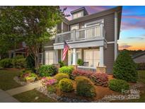Charming two-story home featuring a balcony, well-kept garden, and an inviting facade at sunset at 2007 Bishops Ct, Cornelius, NC 28031