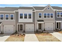 Charming new construction townhomes showcasing varied light gray siding, individual garages, and manicured landscaping at 2720 Lehigh Rd, Charlotte, NC 28208