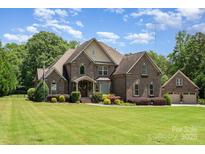 Beautiful brick home featuring manicured lawn and a three car garage on a sunny day at 5183 Mill Race Ln, Lancaster, SC 29720