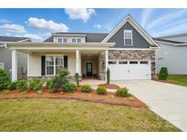 Charming home featuring a manicured lawn, stone accents, and a welcoming front porch at 5723 Notch Peak Ave, Indian Land, SC 29707
