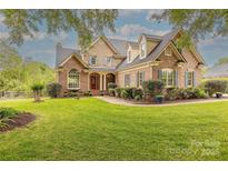 Elegant brick home featuring a lush lawn, blue shutters, mature landscaping, and welcoming front entrance at 6024 Highview Rd, Weddington, NC 28104