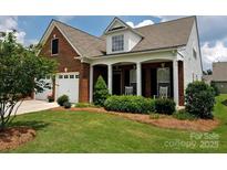 Charming brick home with a covered front porch, well-maintained lawn, and two-car garage at 6310 Highland Commons Rd, Charlotte, NC 28269