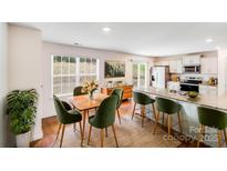 Bright dining area features a wooden table with six green chairs, a sideboard, and a large window at 7205 Finnigan Rd, Charlotte, NC 28215