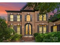 Elegant brick home featuring an arched doorway, complemented by dark shutters and manicured landscaping at 9625 Donna Ve Ln, Charlotte, NC 28277