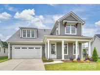 Charming gray two-story home with a welcoming front porch and attached two-car garage at 13618 Tranquil Day Dr, Matthews, NC 28105