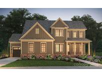 Charming two-story home featuring a landscaped yard, covered front porch, and attached garage at 14213 Kershaw Cir # 15, Huntersville, NC 28078