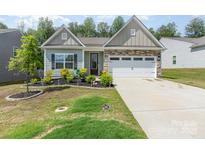 Charming single-story home with a stone and siding exterior and well-manicured front yard landscaping at 160 Tanner Loop, Troutman, NC 28166