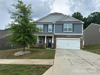 Inviting two-story home featuring a two-car garage, stone accents, and a well-manicured front lawn with landscaping at 184 Cherry Birch St, Mooresville, NC 28117