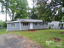 Charming single-story home with gray siding, black shutters, and a well-maintained front yard and mature trees at 2409 Thornton Rd, Charlotte, NC 28208