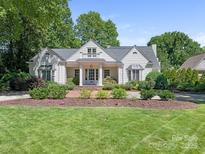 Charming home featuring a lush lawn and beautifully landscaped front yard with mature trees and flowering plants at 2410 Vernon Dr, Charlotte, NC 28211