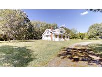 Two-story home with a brick chimney and a inviting front porch nestled on a lot with mature trees at 2645 Kool Park Ne Rd, Hickory, NC 28601