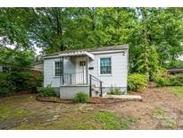 View of the home's exterior with a quaint porch, surrounded by lush green trees at 2905 Grimes St, Charlotte, NC 28206