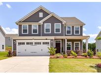 Charming two-story home boasts a well-manicured lawn, a two car garage, and beautiful landscaping at 3023 Ballester Rd, Fort Mill, SC 29707