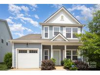 Charming two-story home with a light blue exterior, inviting front porch, and attached garage with white door at 40154 Crooked Stick Dr, Lancaster, SC 29720