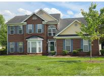Traditional brick home featuring blue shutters, mature landscaping and a well manicured lawn at 6017 Lowergate Dr, Waxhaw, NC 28173