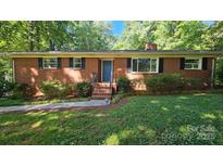 Charming brick ranch home with a blue door and well-maintained landscaping, surrounded by mature trees at 7021 Linda Lake Dr, Charlotte, NC 28215
