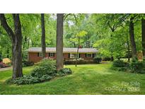 Quaint brick ranch-style home nestled among mature trees with lush landscaping and inviting curb appeal at 7021 Linda Lake Dr, Charlotte, NC 28215
